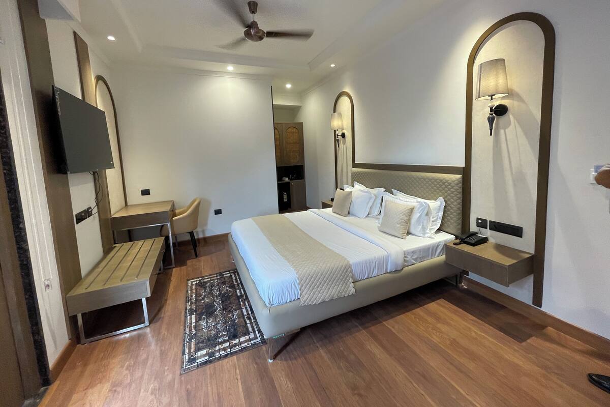 Une chambre d’hôtel moderne équipée d’un grand lit, d’un bureau, d’une chaise, d  ’un ventilateur de plafond et d’un téléviseur fixé au mur.