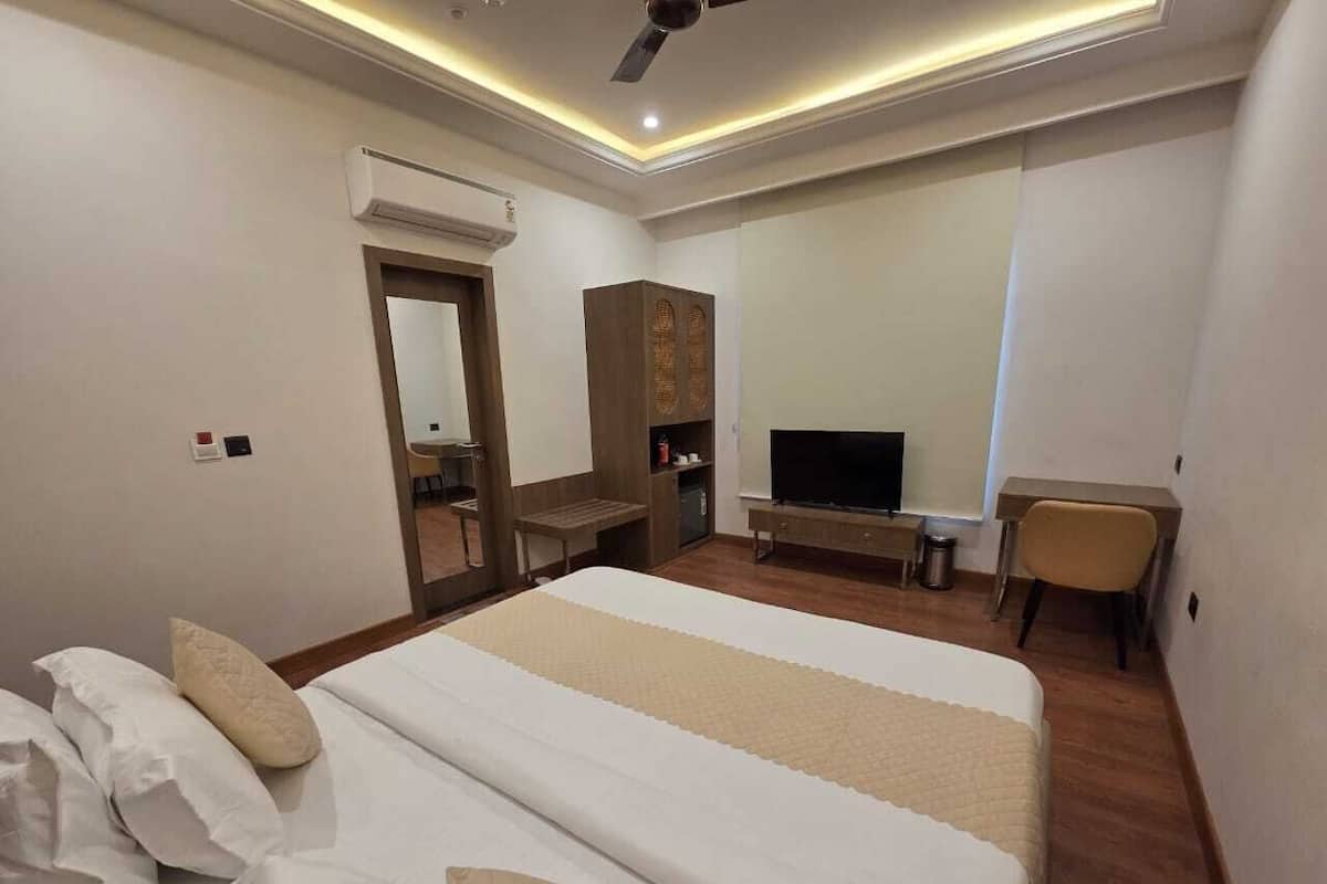 Une chambre d’hôtel avec un grand lit, un bureau, une télévision et une armoire.