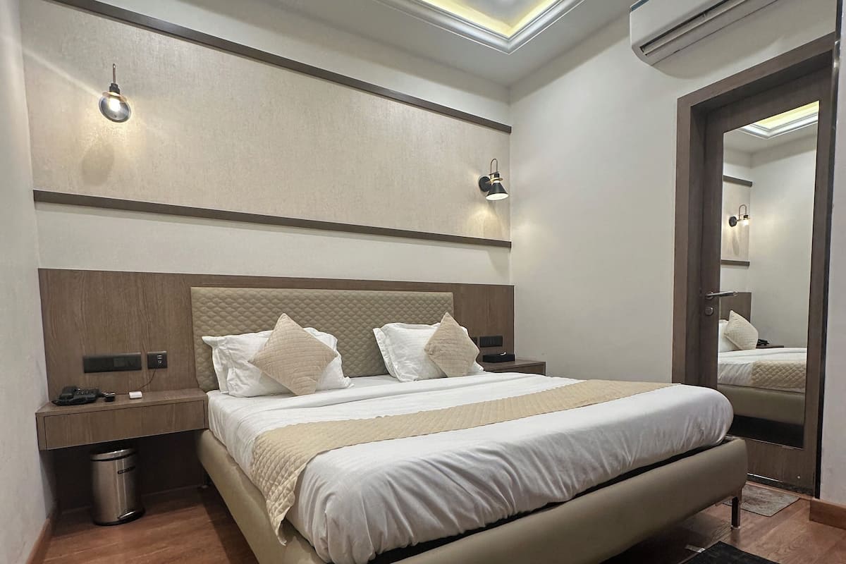 Une chambre moderne avec un grand lit, des tables de chevet, un ventilateur de plafond et un appareil de climatisation.