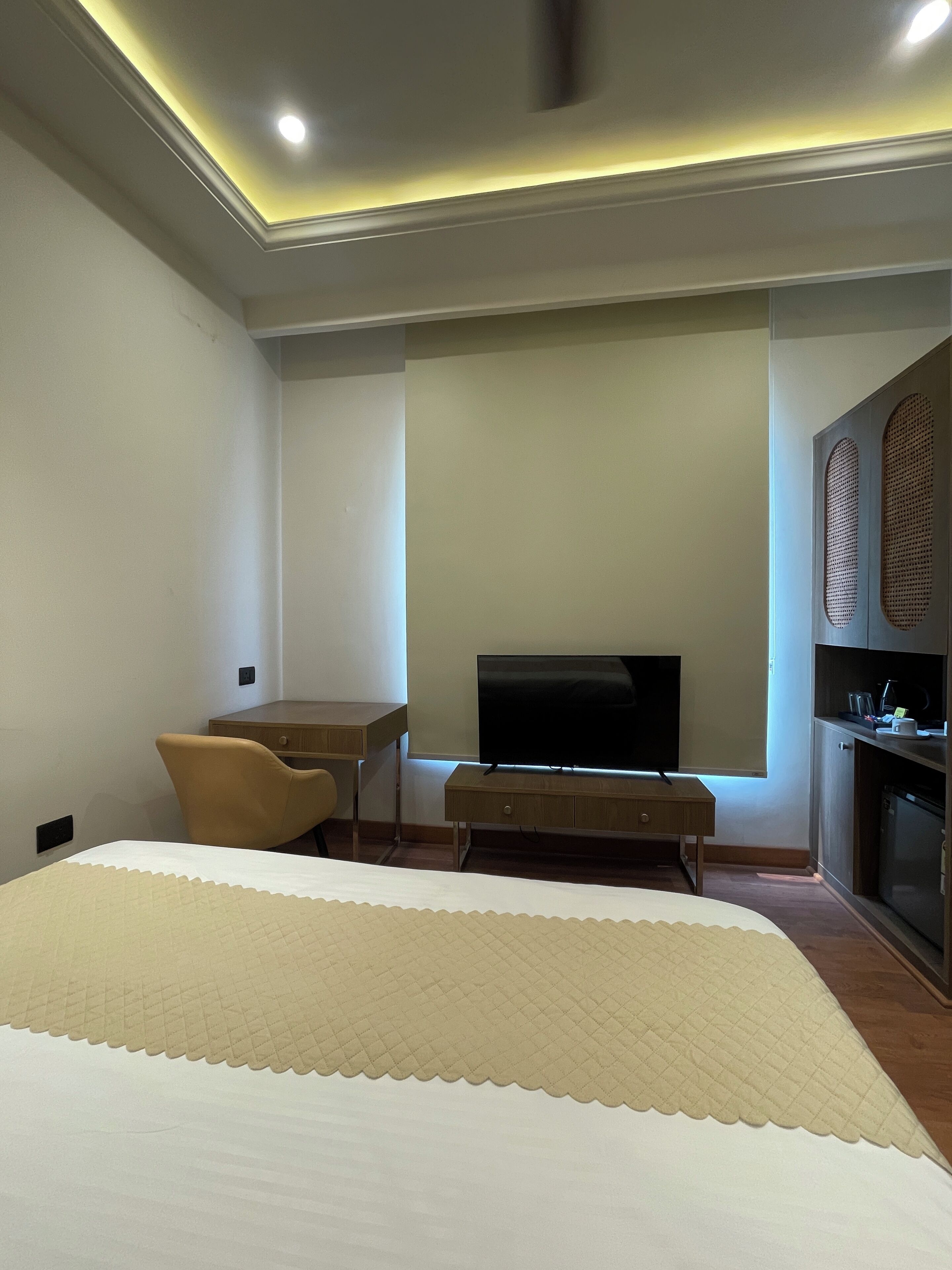 A hotel room with a bed, a desk, a television, and a kitchenette.