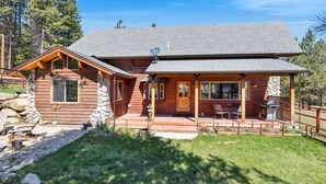 Eine Blockhütte mit Veranda, Steinuntergrund und Satellitenschüssel.