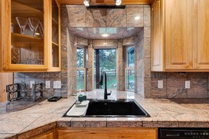 A kitchen with granite countertops, wooden cabinets, and a black sink.