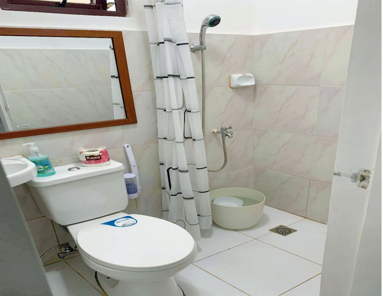 A bathroom with a toilet, a shower, a sink, and a mirror.
