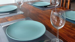 A dining table with teal plates, clear wine glasses, and a wooden table surface. - Modern Unit Cook  Work in Comfort (Motherwell)