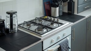 A kitchen with a gas stove, a coffee maker, and a knife block. - Modern Unit Cook  Work in Comfort (Motherwell)
