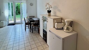 A compact kitchen with a refrigerator, a coffee maker, and a small table with chairs. - Small idyll: Quiet & relaxing - Peter M22 (Stadtsteinach)