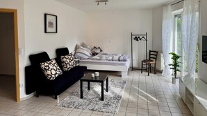 A modern living room with a sofa, a bed, a coffee table, and a TV. - Small idyll: Quiet & relaxing - Peter M22 (Stadtsteinach)