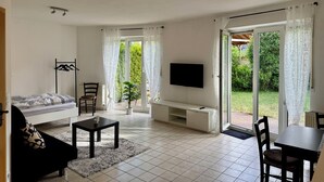 A spacious living room with a sofa, a coffee table, a TV, and a dining area. - Small idyll: Quiet & relaxing - Peter M22 (Stadtsteinach)