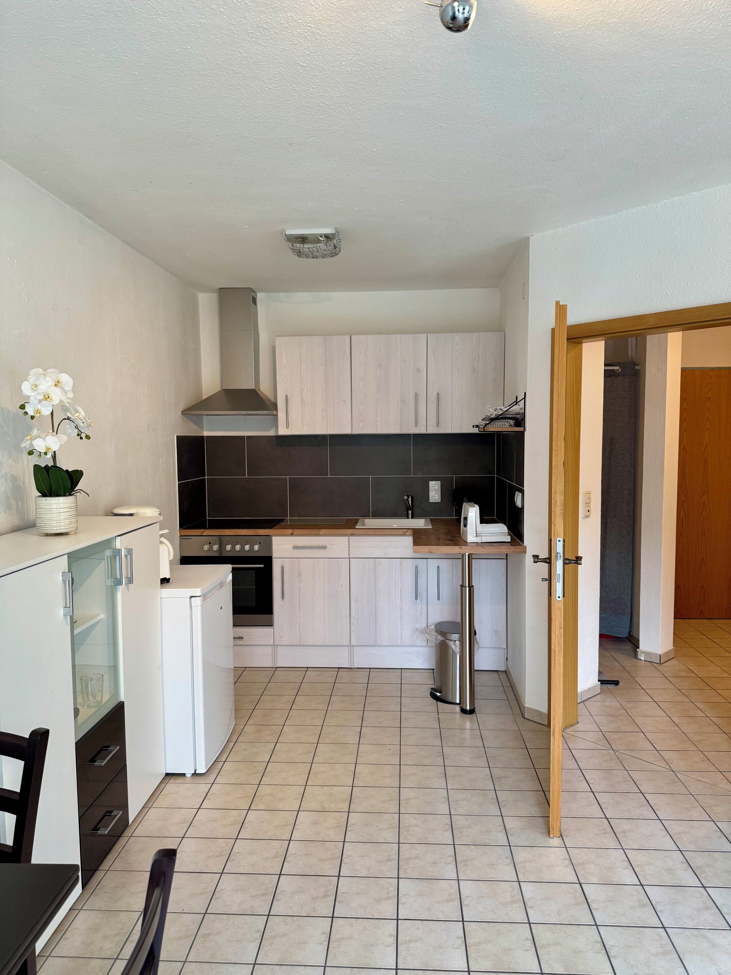 A compact kitchen with white cabinets, a small refrigerator, a stove, and a sink.