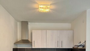 A modern kitchen with light wood cabinets, a stainless steel range hood, a built-in oven, and a black tiled backsplash. - Small idyll: Quiet & relaxing - Peter M22 (Stadtsteinach)