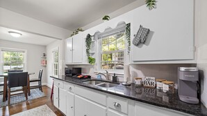 A modern kitchen with white cabinets, a granite countertop, a coffee maker, and a sign that reads "Coffee Bar". - Perfect Lindley Park location - Minutes from GAC, Coliseum, Restaurants and Pubs (Greensboro)