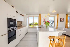 A modern kitchen with white cabinetry, a built-in oven, and a large island with seating.