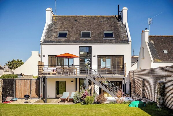 A two-story house with a balcony, a staircase, and a barbecue area.
