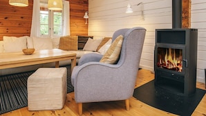 Un interior de cabaña acogedor, con detalles de madera, un sofá, una mesa y una chimenea.