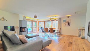 Una sala moderna con sofá, televisor, chimenea y comedor con sillas y mesa.