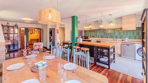 A modern kitchen with a wooden island, bar stools, and a dining area with a table set for four.