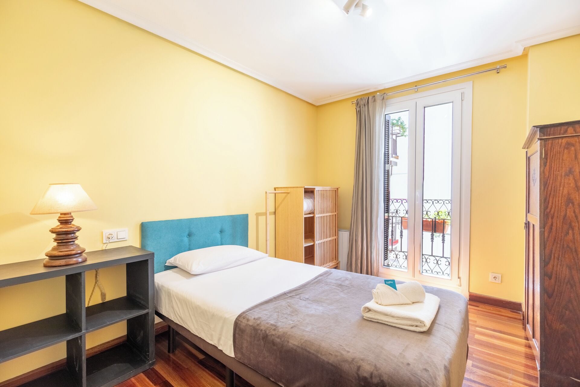 Ein Hotelzimmer mit Bett, Nachttisch mit Lampe, Kleiderschrank und Blick auf den Balkon.