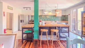 A modern kitchen with a central island, bar stools, and pendant lighting.