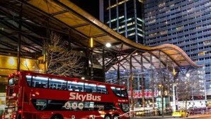 A red double-decker bus with "SkyBus" branding parked at a bus station. - Modern 2-Bedroom Apartment in Melbourne CBD with Balcony, Pool & Gym Access (Melbourne)