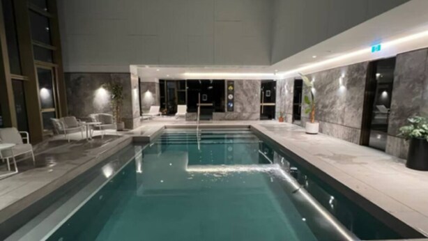 An indoor swimming pool with a modern design, surrounded by marble walls and equipped with lounge chairs. - Modern 2-Bedroom Apartment in Melbourne CBD with Balcony, Pool & Gym Access (Melbourne)