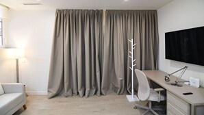 Une chambre moderne équipée d’un bureau, d’une chaise, d’une lampe et d’un grand téléviseur.