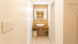 Une salle de bain moderne avec un meuble-lavabo en bois, un grand miroir et un lavabo blanc.