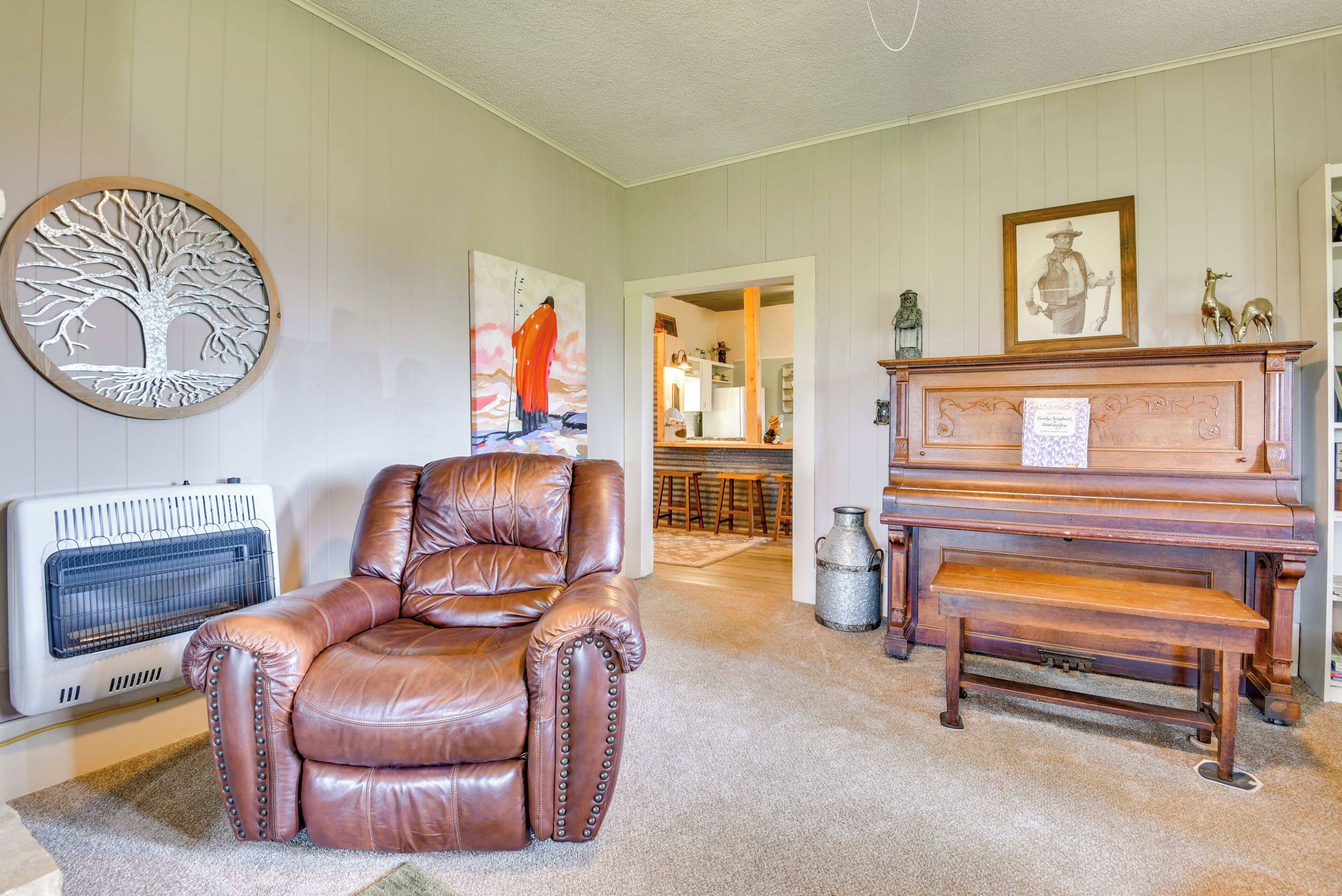 A living room with a leather armchair, a piano, and a radiator.