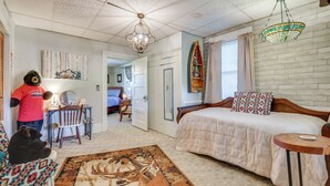 Un dormitorio con cama, escritorio, silla y alfombra.