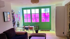 A living room with a dark-colored sofa, a wooden coffee table, and a green door with pink-tinted windows. - Large duplex in the heart of the village of Carnac, near historic sites & beaches (Carnac)