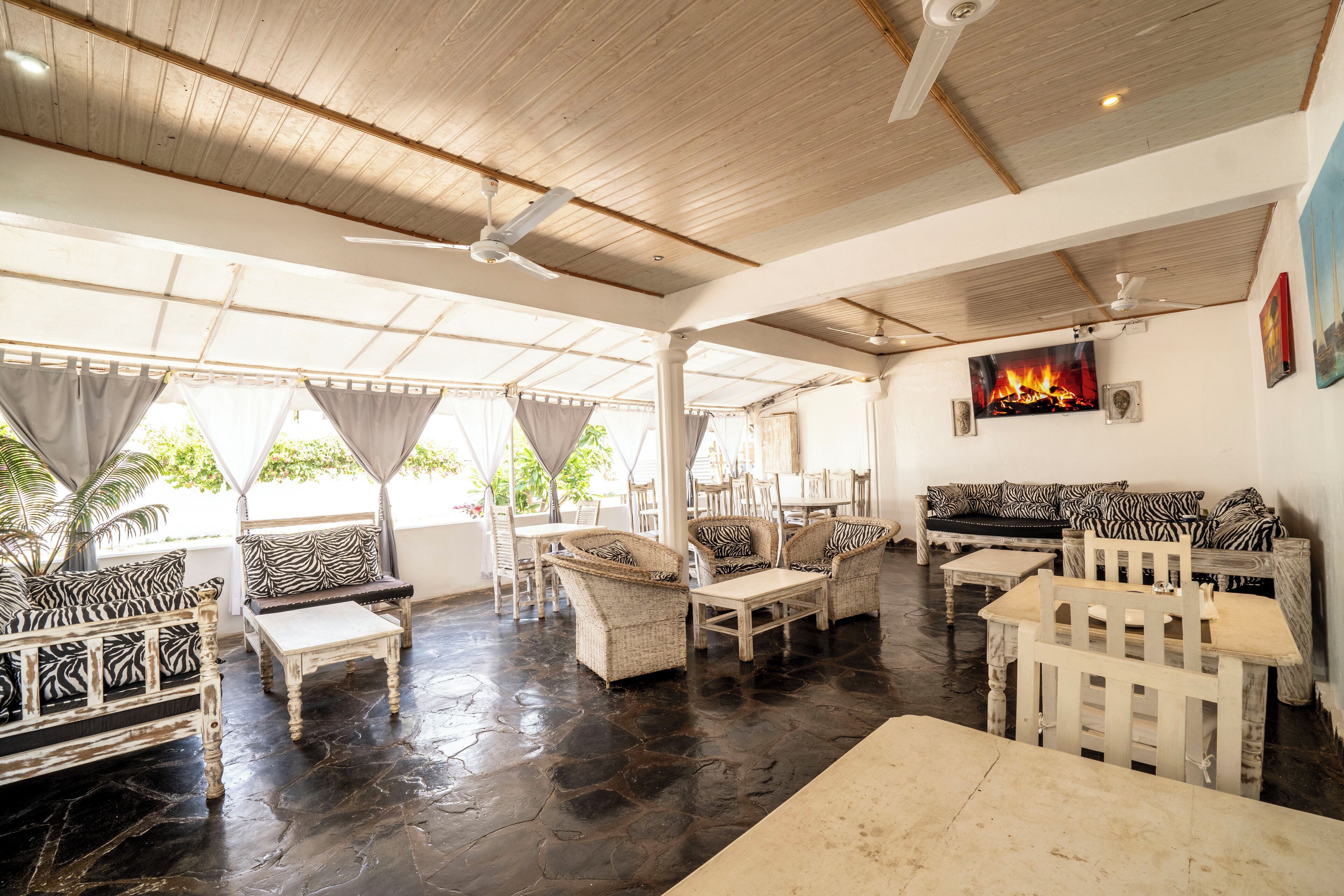 A spacious indoor area with a high ceiling, wooden beams, and a variety of seating arrangements including sofas and chairs.