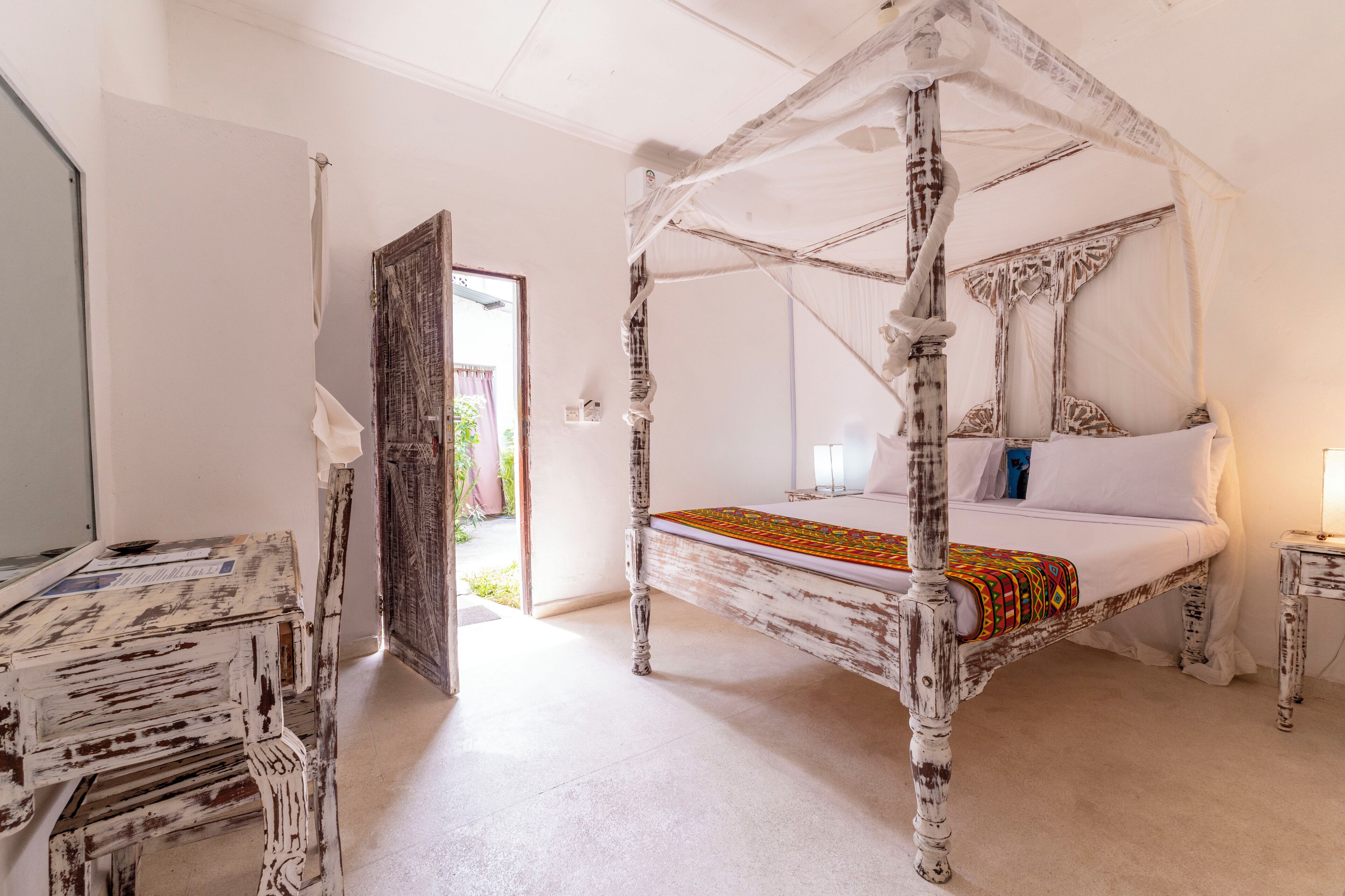 Une chambre avec un lit à baldaquin, une petite table et une chaise.