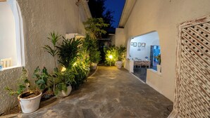 A narrow stone pathway flanked by potted plants and a white wall with a woven door. - Paradise Lagoon B&B (Watamu)