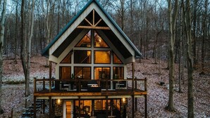 Eine Holzhütte mit einer Holzdiele, großen Fenstern und einem Steinfundament.
