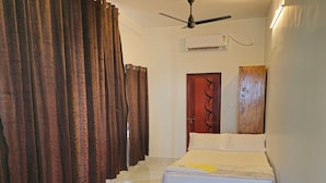 A bedroom with a bed, a ceiling fan, a wooden wardrobe, and a door with a decorative panel. - 😁Welcome to Sailor Homes Beach Resort... (Cherthala North)