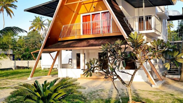 A modern house with a triangular roof and a balcony. - 😁Welcome to Sailor Homes Beach Resort... (Cherthala North)