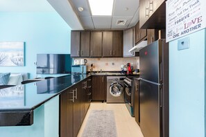A modern kitchen with wooden cabinets, a stainless steel refrigerator, a washing machine, and a flat-screen TV. - Bloomfields Stunning Sea view in Hydra  (Abu Dhabi)