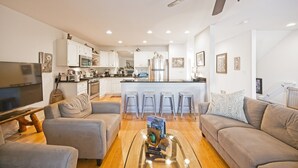 A modern living room with a glass coffee table, two sofas, a TV, and a kitchen in the background. -  Dells treetop lakeside lodging on famous Canyon Road. A top location! (Wisconsin Dells)