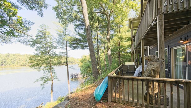 A wooden deck with a blue slide, overlooking a lake and surrounded by trees. -  Dells treetop lakeside lodging on famous Canyon Road. A top location! (Wisconsin Dells)