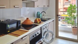 Une cuisine moderne avec des meubles blancs, un four à micro-ondes, une cuisinière et un lave-linge.