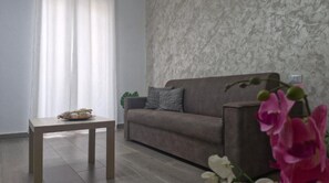 Un salon avec un canapé, une petite table et une plante décorative.