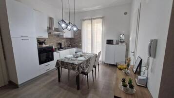 Una cucina moderna con mobili bianchi, un tavolo da pranzo per quattro persone e un forno integrato.