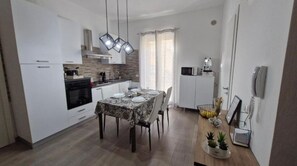 A modern kitchen with white cabinets, a dining table set for four, and a built-in oven.