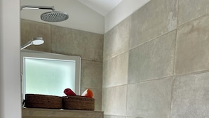 A bathroom with a shower, a window, and a towel rack with a basket.