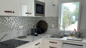 A modern kitchen with white cabinets, a built-in microwave, a sink, and a dishwasher.
