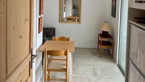 A dining area with a wooden table and chairs, a mirror on the wall, and a lamp on a small table.