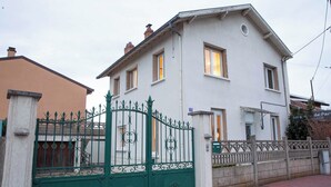 Una casa de dos pisos con una reja verde de hierro forjado y fachada blanca.