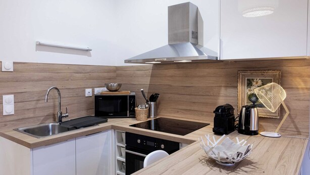 Una cocina moderna con un lavamanos de acero inoxidable, electrodomésticos negros y una encimera de madera.