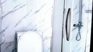 A bathroom with a toilet, a shower, and marble walls. - A cosy sleep out in backyard (Kennington)