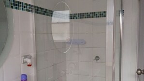 A bathroom with a white sink, a mirror, a shower with a glass door, and a tiled floor. - A cosy sleep out in backyard (Kennington)