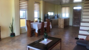 A spacious living area with a dining table, chairs, a coffee table, and a sofa. - Modern Duplex 2-Bedroom Apartment with Sea View of Baroro Beach. (Bacnotan)